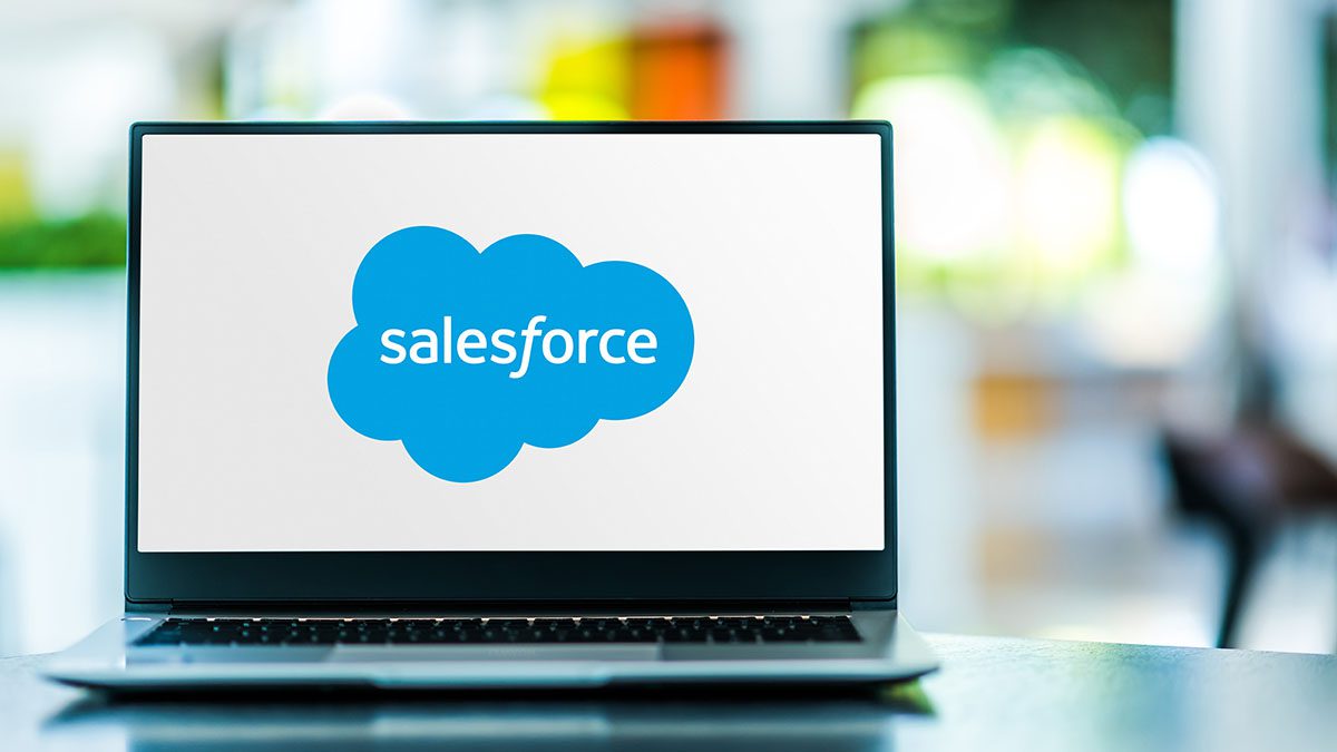 Salesforce logo displayed on a laptop screen in a bright, modern office setting.